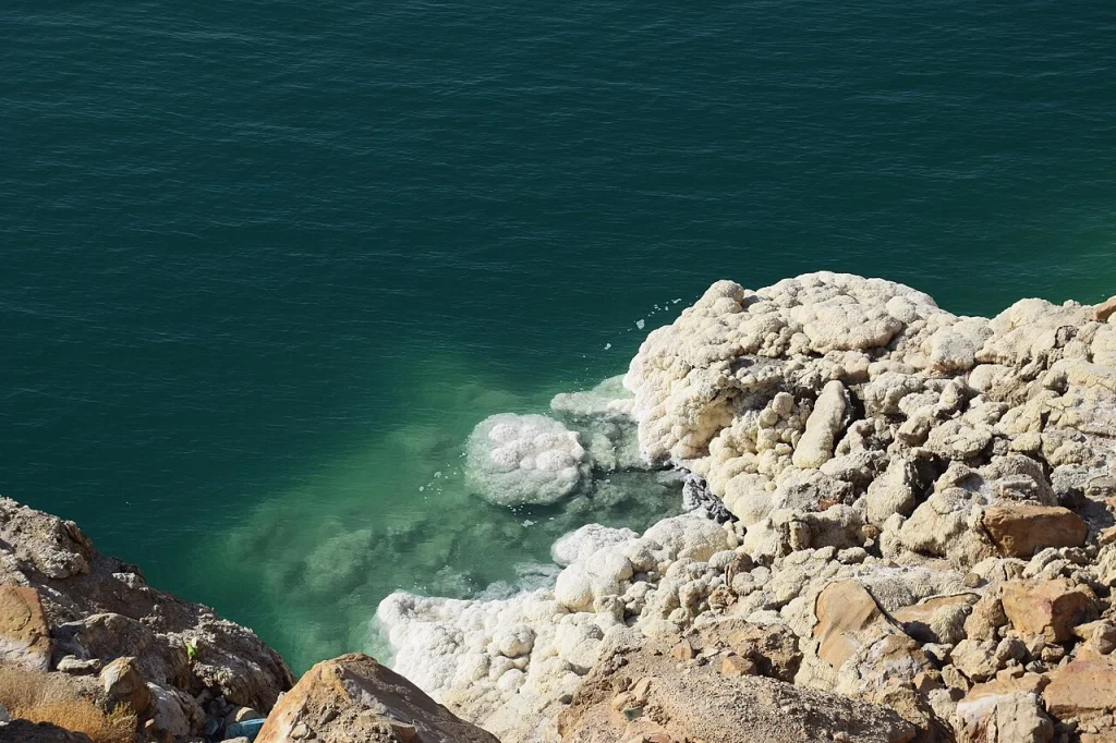 White salt deposits on rocks beside blue water on the Jordanian Dead Sea coast